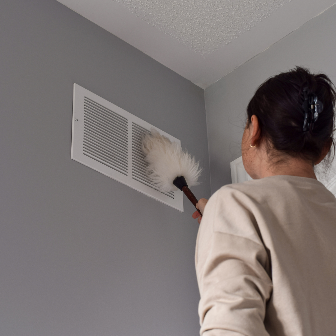 A women dusting a air vent