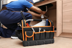 Homeowner checking under a bathroom sink for plumbing issues such as leaks, moisture, or loose connections.